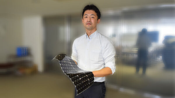 化合物事業推進部 主任の植田 浩介 手に持つのは、ドローンなどの無人航空機向けの太陽電池モジュール