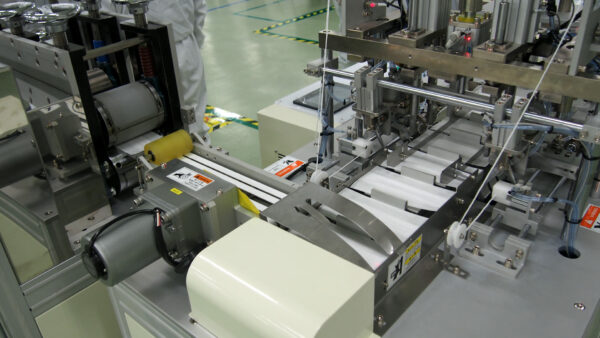 左奥のカッターで裁断、マスク形状（長方形）に